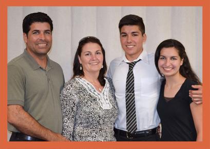 A family posing for a picture in front of white curtains.