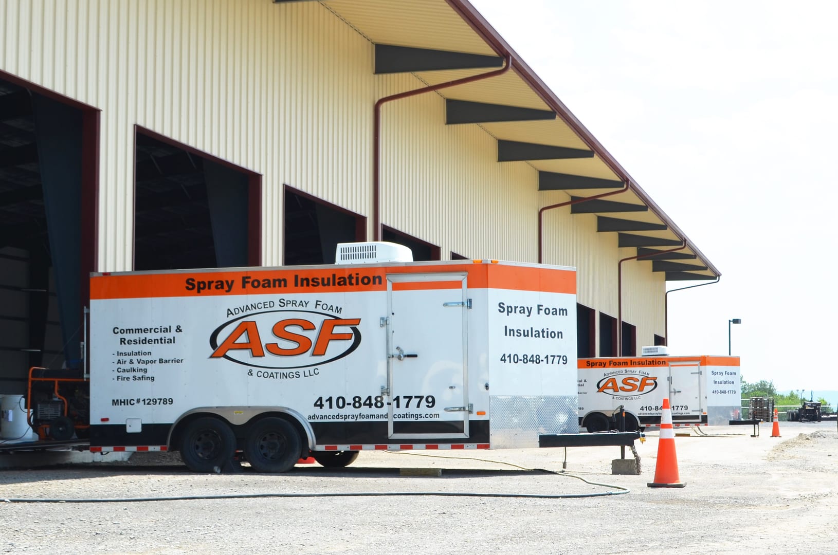A white trailer with orange lettering parked in front of a building.